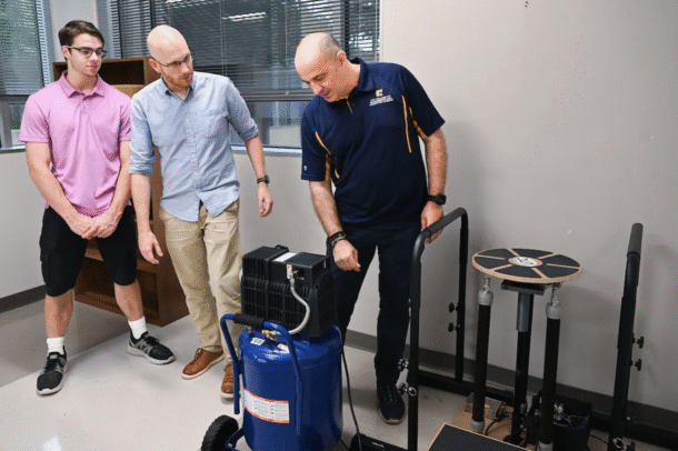 Mechatronics major Austin McDade, left, Dr. Max Jordon and Dr. Erkan Kaplanoglu demonstrate the pneumatically powered balance board.